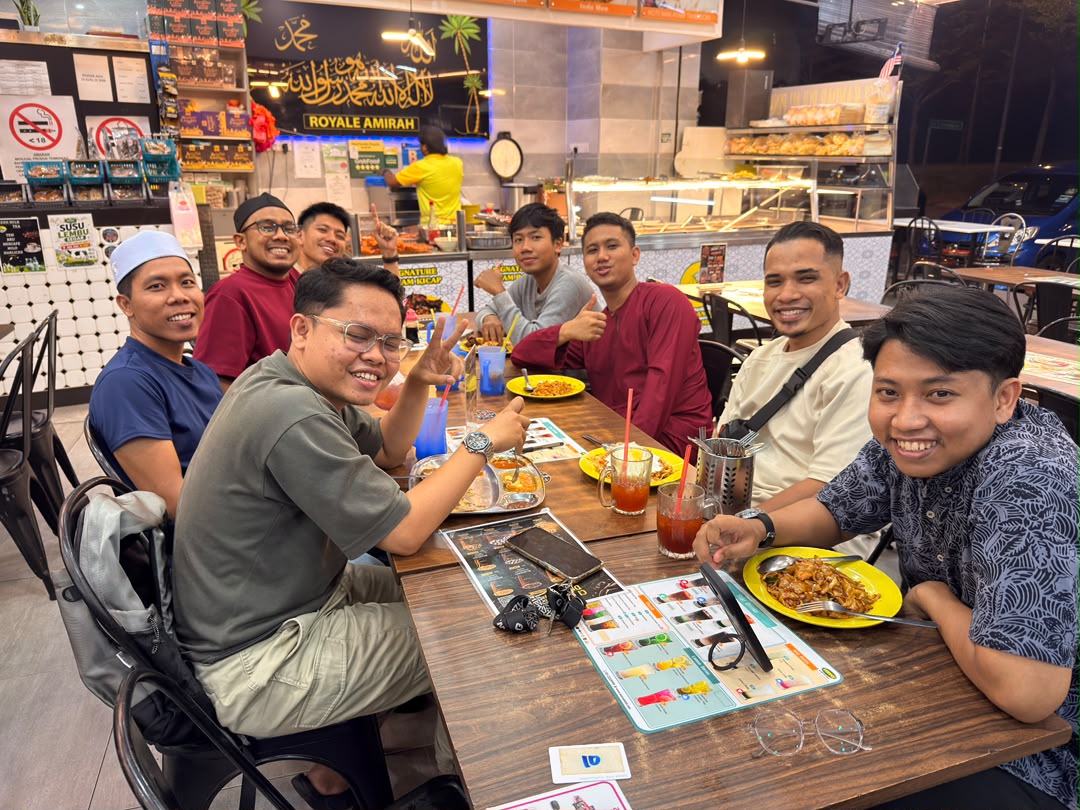 Ahli komuniti makan bersama di meja panjang selepas perjumpaan